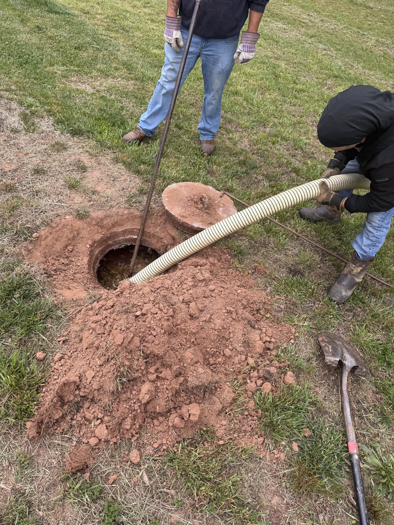 Palmer Septic crew working a septic tank — gloved, gear in hand, hose ready