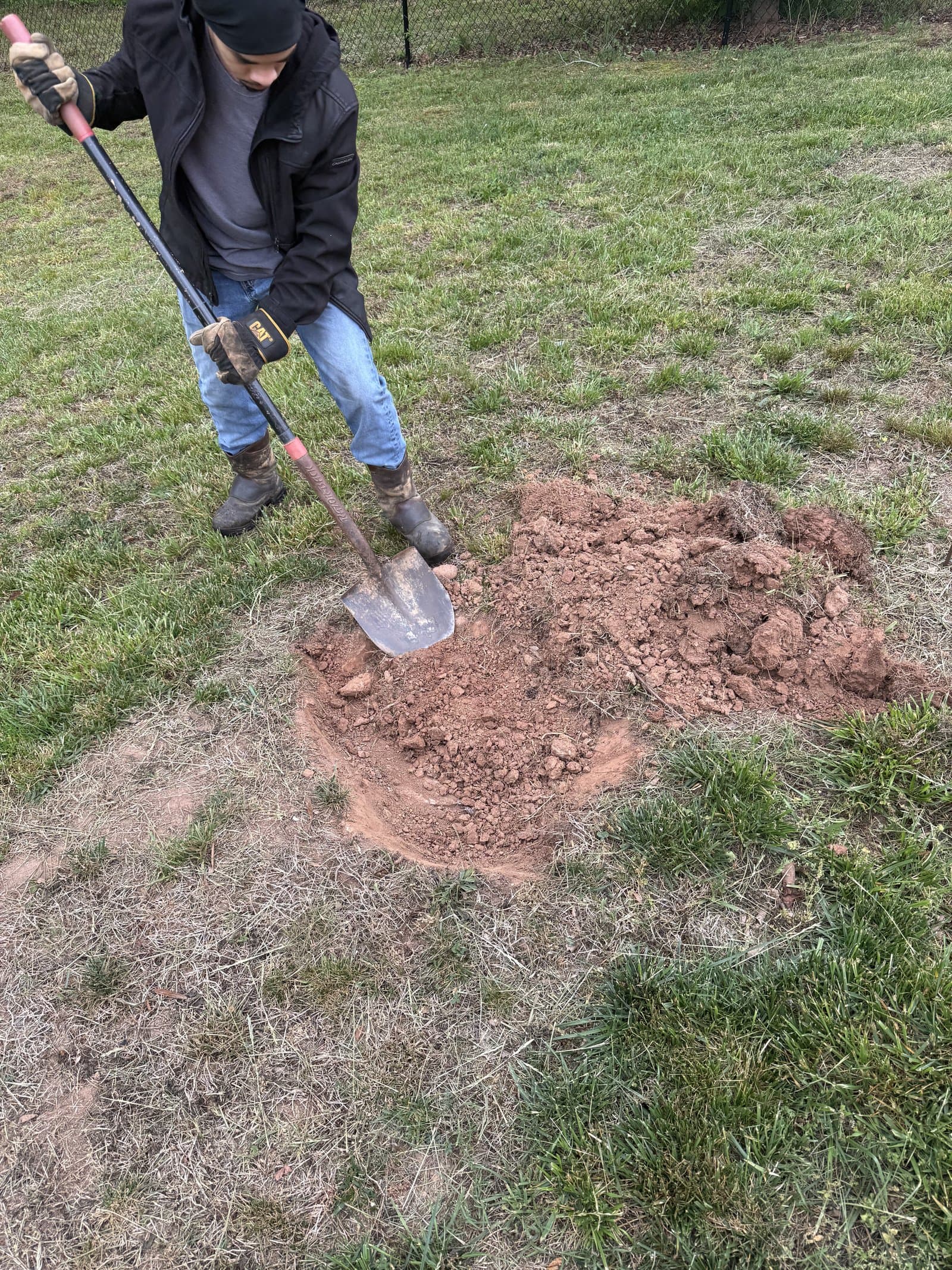 Technician with a shovel excavating to reach a buried septic tank lid